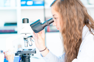 girl in biological class research with microscope