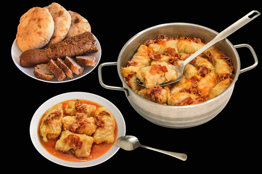 Plateful Of Cabbage Rolls Stuffed With Minced Meat Cooked With Smoked Ham Slices In Stainless Steel Saucepot And Pitta Bread Loafs With Sliced Baguette Isolated On Black Background