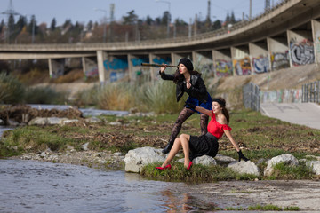 Two fashionable women with a telescope at a river
