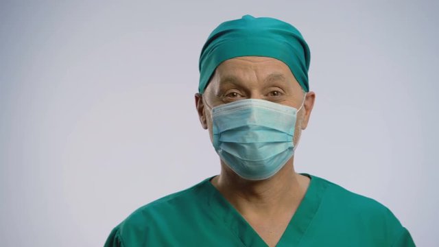 Funny man wearing scrubs and face mask pretending to be proctologist, crazy joke