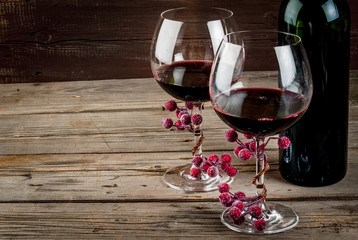 Bottle of wine and two glasses of wine, decorated with artificial branch of winter berries. The...