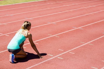 Fototapeta premium Female athlete ready to run on running track
