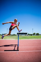 Female athlete jumping above the hurdle