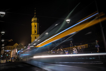 Fototapeta na wymiar Strassenbahn-Lichtzieher vor Grazer Franziskanerkirche und Weihnachtsmarkt in der Adventzeit