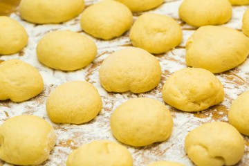 Fototapeta na wymiar Raw donuts lying in flour on wooden table