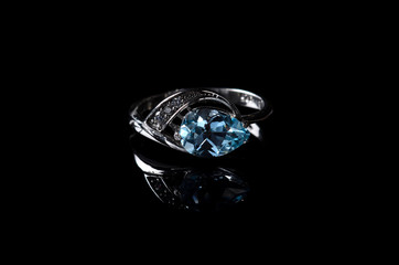 Silver ring with blue topaz isolated on a black background.