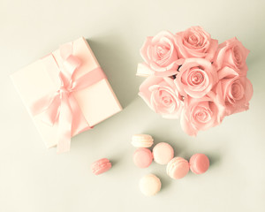 White box with red bow, French macarons and roses flat lay
