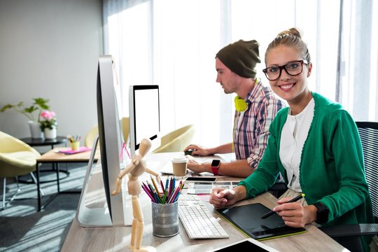 Casual colleagues using graphic tablet and computer