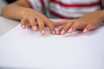 Obraz na płótnie Canvas Child reading braille book in classroom