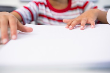Child touching braille book in classroom