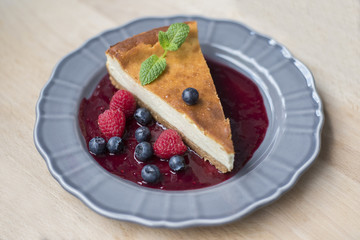 Cheesecake with raspberry puree on grey plate