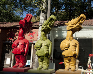 Three sculptures in different colors  with human bodies and Chinese dragon heads.