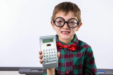 Smiling boy holding calculator in classroom