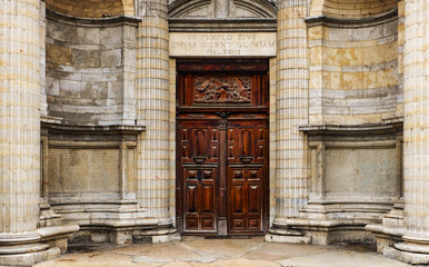 Heavy wooden double door outside of an old church. Circle wall with square stones and pillars....
