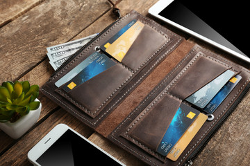 Leather wallet and modern devices on wooden background