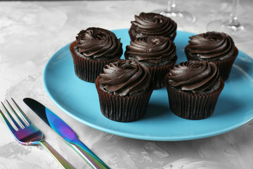 Tasty cupcakes with cutlery on blue plate