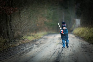 Young boy playing outdoor with wooden sword