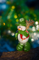 Snowman with a broom on a background of blurred Christmas tree