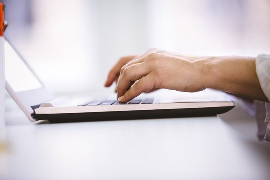 Cropped image of businesswoman typing on laptop at office