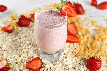 Fresh milkshake with berries, cereals and oatmeal on wooden table closeup