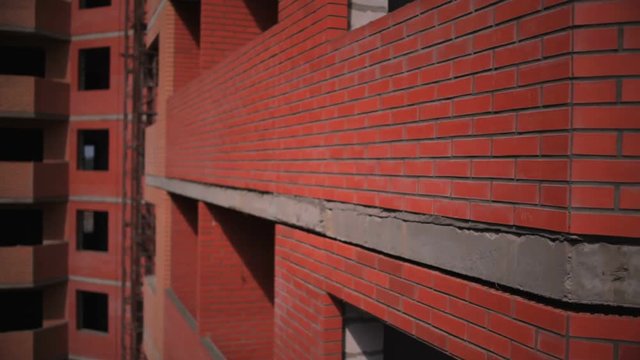 Development projects of factories . The camera goes up along the wall of a brick house. In the background an unfinished house