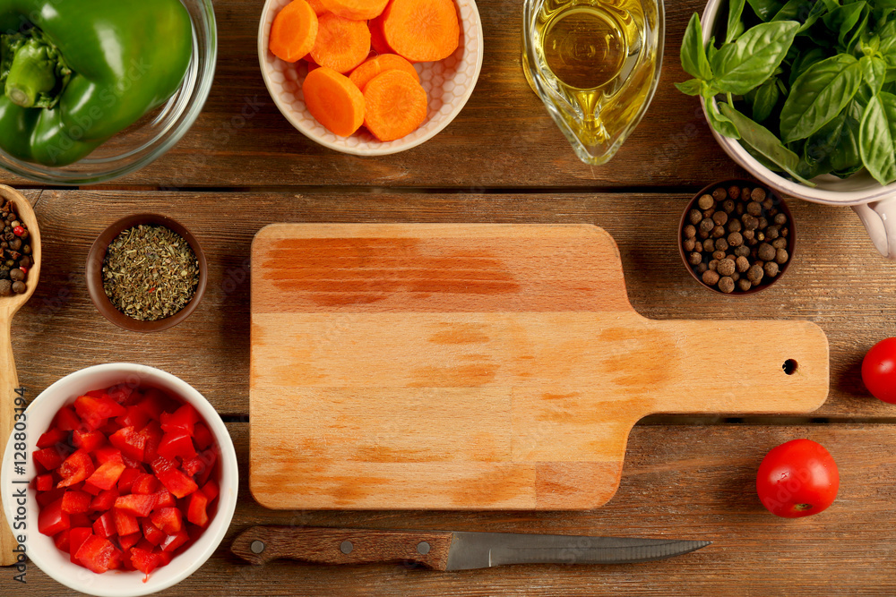 Wall mural Fresh vegetables for salad with wooden cutting board on table