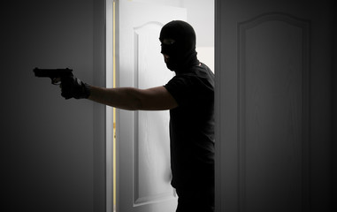 Male thief with gun entering the room