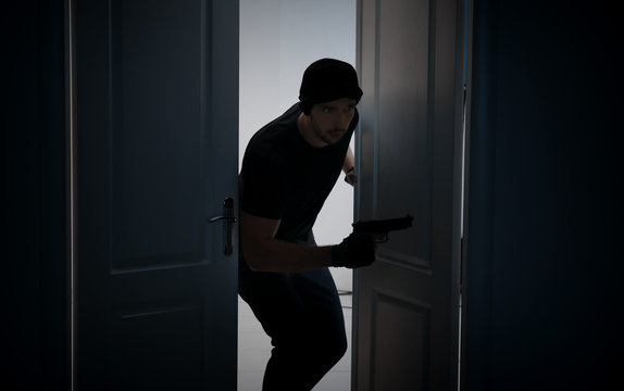 Male thief with gun entering the room
