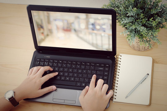 Hand typing laptop with blank blur background on screen