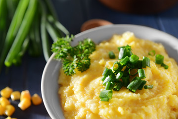 Tasty breakfast of cornmeal porridge with parsley and green onion, closeup