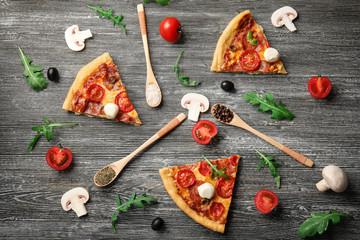 Pizza slices with ingredients on wooden table