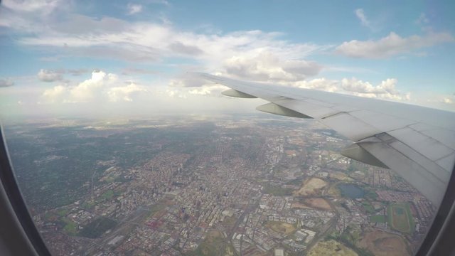 In-flight Airliner Wings Over Johannesburg South Africa Seen from Passenger Window with City Center Buildings Underneath on a Sunny Day with a Blue Sky