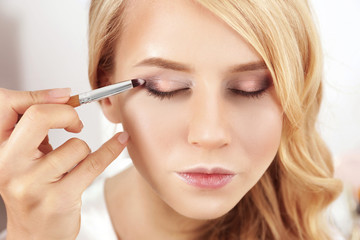 Artist applying eye shadow on beautiful woman eyes