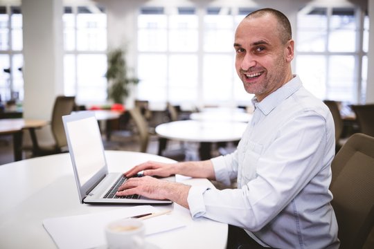 Portrait of happy executive with laptop at creative office