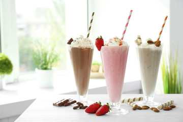 Delicious milkshakes on table in kitchen