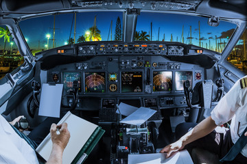 Airplane cockpit flying on Ala Wai Harbor, Honolulu by night, Oahu, Hawaii, with pilots arms and...