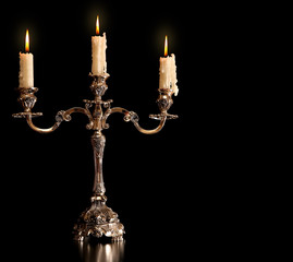 burning old candle vintage bronze Silver candlestick. Isolated Black Background. - obrazy, fototapety, plakaty
