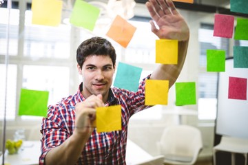 Businessman writing on multi colored sticky notes