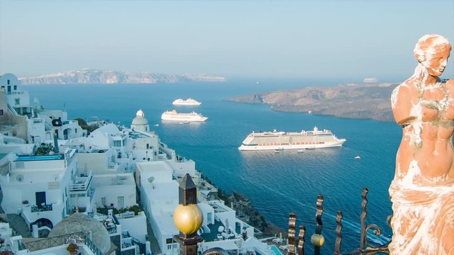 Santorini Greece Picturesque Morning View from Thira Town featuring a Statue and Greek Style Buildings on Top of the Mountain Overlooking the Ocean with Visiting Cruise Ships