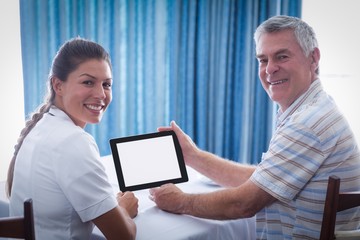Portrait of senior man and female doctor using digital tablet