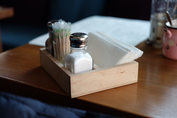 Fototapeta na wymiar Part of restaurant table setting salt, pepper, toothpicks and paper napkins in wooden box on table 