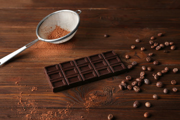 Chocolate with sieve and beans on wooden table