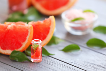 Grapefruit, leaves and bottle with essential oil on wooden table