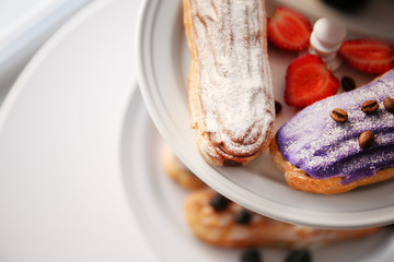 Delicious colourful eclairs with berries on dessert stand, closeup