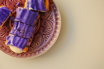 Tasty sliced eclair with cream on pink plate and light background