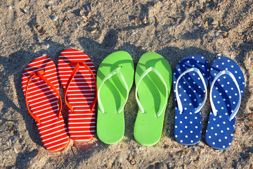 Colorful sandals on sea beach, close up view