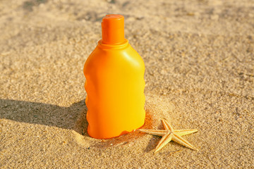 Sunscreen cream and starfish on sea coast, close up view