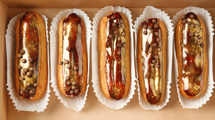 Delicious eclairs in cardboard box, top view