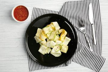 Slices of zucchini with seasoning on black plate