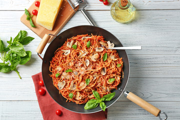 Pan with delicious pasta, products and napkin on wooden table